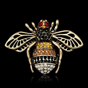 Macro shot of bee brooch with colorful rhinestones and gold details on black background