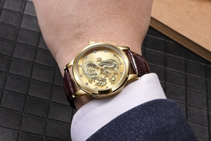Macro detail of men's gold watch with dragon relief and leather strap on wrist
