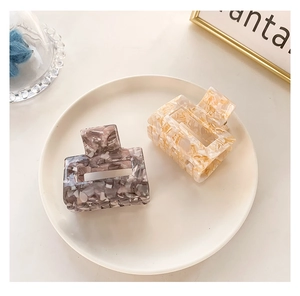 Detail of square cutout claw clips with marble pattern in cream and deep purple colors