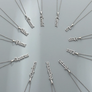 Silver stainless steel zodiac necklaces with Old English pendants on grey background