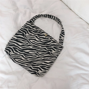Close-up of zebra print canvas tote bag featuring a brass magnetic buckle closure