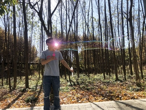 Outdoor bubble wand toy creating long bubbles in natural park light setting