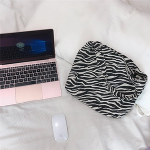 Detail of minimalist zebra print canvas shoulder bag on a white fabric background