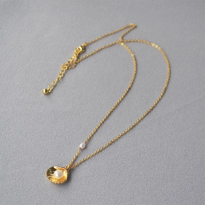Close-up of gold shell pendant with pearl on a thin adjustable chain necklace