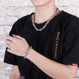 Silver stainless steel chain necklace and bracelet set shown on model against white wall