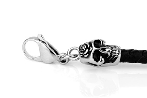 Close-up of black braided leather bracelet with silver skull charm and lobster clasp
