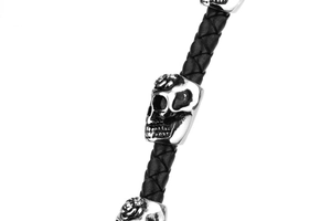Close-up of woven black leather bracelet featuring a silver skull with rose engraving