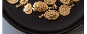 Detailansicht von Vintage 18K vergoldeten Herz- und Münzanhängern auf einem schwarzen Tablett
