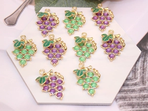 Detailed view of grape-shaped alloy charms with purple and green enamel in a DIY jewelry set