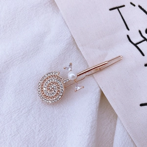 Close-up of golden hair clip with sparkling rhinestones, white pearl and crystal detail
