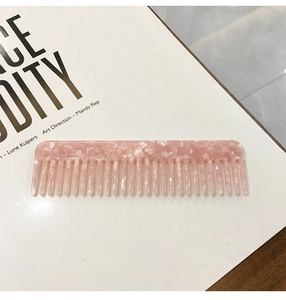 Detailed macro view of pink marble acetate hair comb with smooth rounded edges
