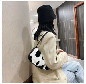 Detail view of stylish zebra print plush shoulder bag worn by model in minimalist setting
