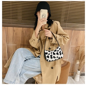 Street style shot of a plush zebra print underarm bag paired with a khaki trench coat