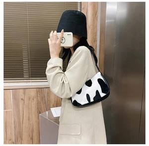 Close-up of zebra pattern plush shoulder bag worn by model in a modern interior