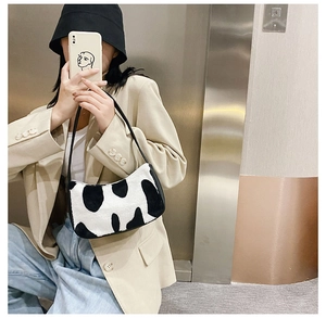 Detail shot of plush black and white cow print shoulder bag with sleek leather strap