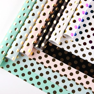 Assorted gold polka dot gift wrapping paper rolls in mint, pink, and white colors