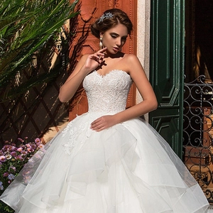 Elegant white strapless wedding dress with floral lace bodice and layered tulle skirt