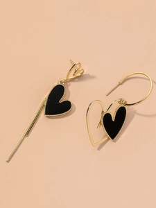 Close-up of asymmetric gold and black heart earrings with sleek enamel finish
