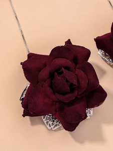 Close-up of retro dark red fabric rose pendant with silver hollow metal leaf details