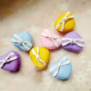 Macro detail of colorful heart macaron charms with white bows for DIY jewelry and phone cases