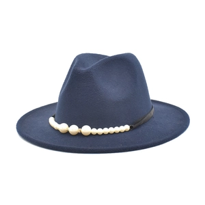 Detail of dark blue wool fedora hat featuring elegant faux pearls and rhinestone trim