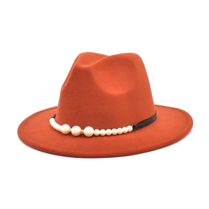 Close-up of orange wool fedora hat with black band and pearl embellishments