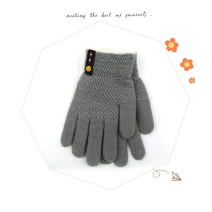 Detail of grey knitted children's gloves featuring a smiley face and BABY label accent