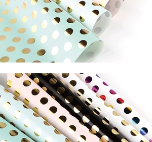Close-up of metallic gold polka dots on colorful gift wrapping paper rolls