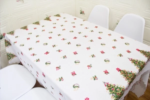 Detail of Christmas tablecloth featuring festive holiday patterns on white fabric background