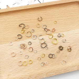 Assorted jewelry jump rings in multiple sizes and metallic colors on wooden tray