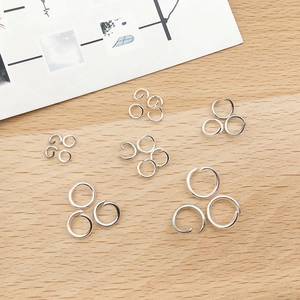Various sizes of silver open jump rings for DIY jewelry making on wooden background