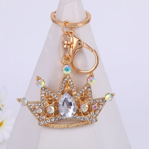 Elegant gold crown keychain with sparkling rhinestones on a minimalist white stand