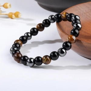 Close-up of tiger eye, obsidian, and hematite beads bracelet on a rustic wood background