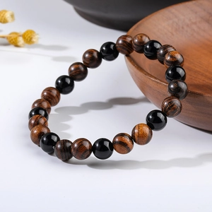 Detail of tiger eye and sandalwood beaded bracelet on a serene white background