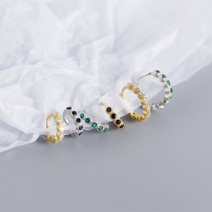 Detail of S925 sterling silver ear cuffs with clear, black, and green zircons on silk paper
