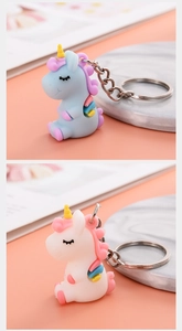 Close-up of blue and white soft PVC unicorn keychains with silver metal rings