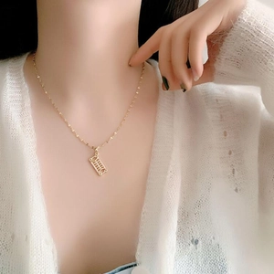 Close-up of a delicate golden abacus pendant necklace on a model's collarbone
