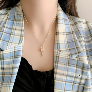 Detailed close-up of a gold lock and key pendant necklace with micro-pave zircon crystals