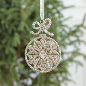 Glittering gold Christmas bow and snowflake ornament hanging on a festive green tree