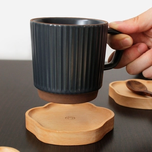 Minimalist bear paw wooden coaster with gray ceramic mug and spoon on dark desk