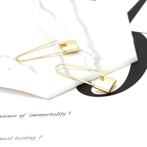 Detailed view of gold plated safety pin earrings on a marble texture display tray