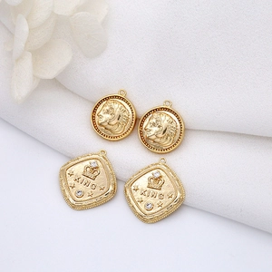 Close-up of 14K gold coin pendants with classic portraits and King crown engravings