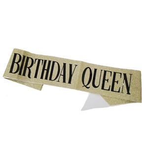 Detail of golden glitter sash with black Birthday Queen text for party decoration