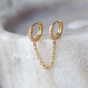 Macro detail of gold-plated double hoop earrings with cubic zirconia and chain link
