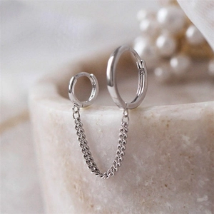 Macro detail of silver long chain earrings with double hoops on stone display