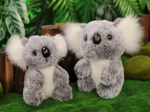 Detail of two plush koalas with fluffy ears and soft gray fur on a natural wood log