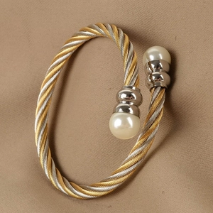 Detail of twisted gold and silver steel wire bracelet with elegant white pearls