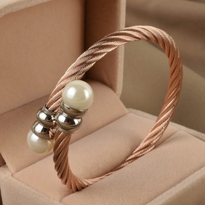 Macro detail of rose gold cable twist bangle featuring two lustrous white pearls on ends
