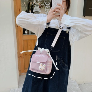 Detail of cute rabbit ear bucket bag with purple plaid canvas and plush bunny decor