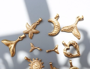 Detailed close-up of 18k gold plated moon and starfish charms on a grey background